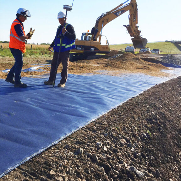 Adding dirt and stone over ground-reinforcement geotextile.