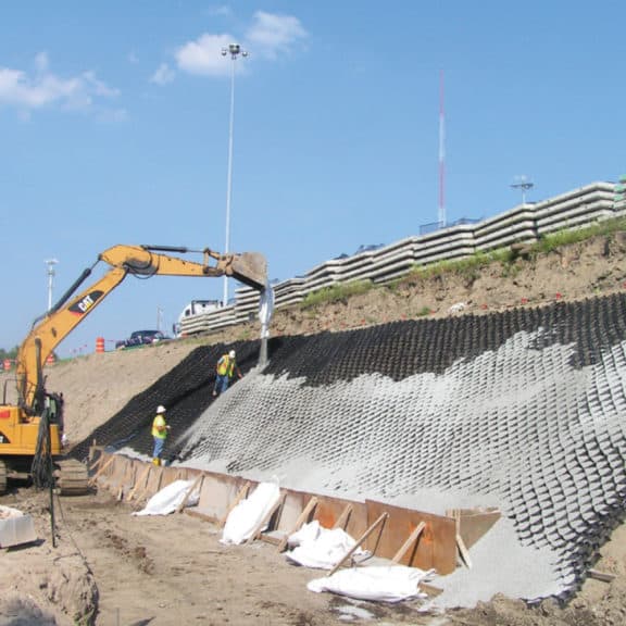 Large excavator applying AquaBlok stones to a slope