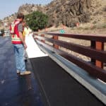 Contractors simply peeling off the back of Petrotac Self-Adhesive Paving Membrane & installing it on a bridge