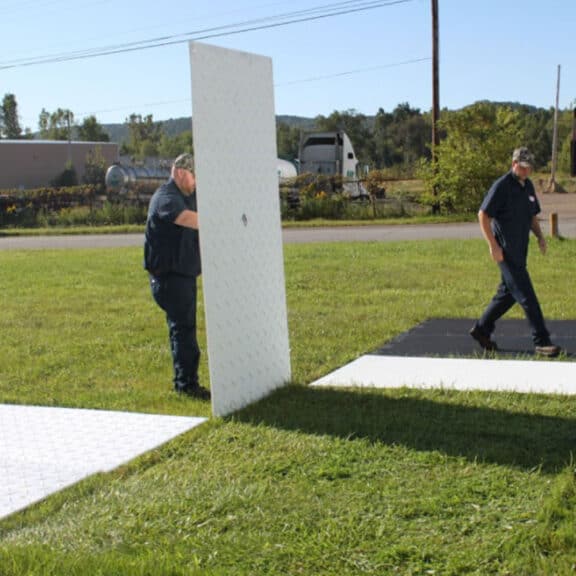 Installing clear ground protection mats on green grass for event