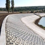 Fabric formed concrete, or grout mattress along a channel