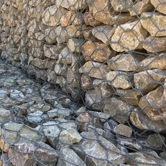 Stacked gabion rock cages forming retaining wall