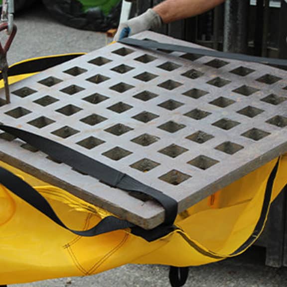 Workers fitting the built-in straps of the EconoSack to a storm grate that has been removed