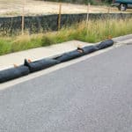 Several GutterEELs lined up on a curb-side runoff drain