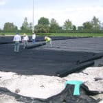 Construction crew installing nonwoven geotextile on large development site