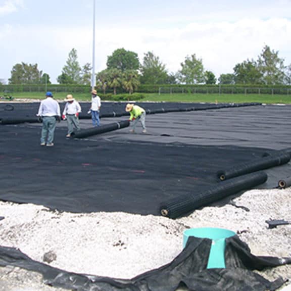 Construction crew installing nonwoven geotextile on large development site