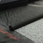 Placing medium-weight geotextile over stone for filtration.