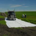 Heavy equipment driving on mud mats across a green field without damaging the grass