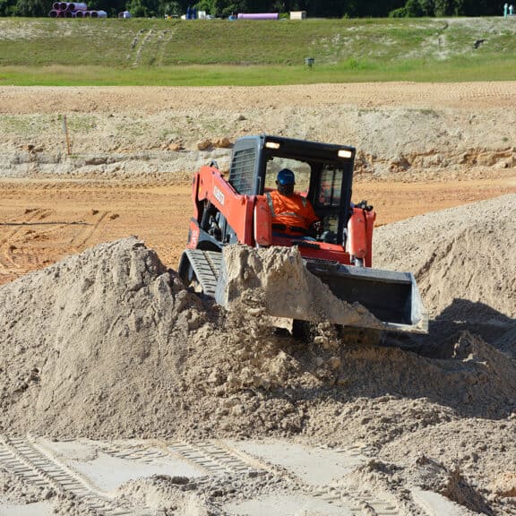 A large Ferguson Waterworks truck dumping filtration media on a job site