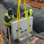 Construction workers guiding a porous precast Twall into position