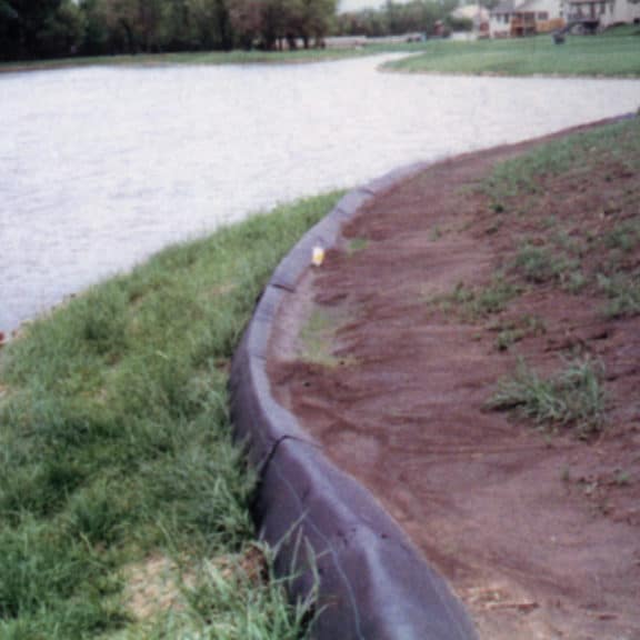 A reusable and lightweight triangular silt dike barrier between a body of water and land.