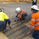 Construction workers installing high-strength ground Uniaxial Geogrid.