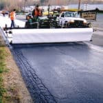 Construction crew using paving fabrics to retard reflective cracking and extend the life of the new asphalt