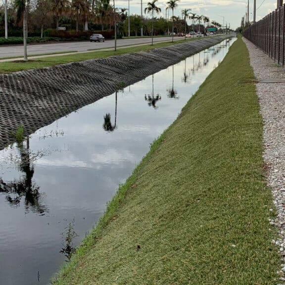 Hard armor system, hydro turf, lining the ditch of a busy street in Naples Florida and preventing both flooding and erosion.