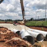 Professionals installation CMP in drainage field for managing stormwater