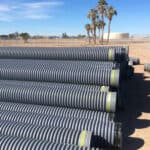 A large stack of corrugated HDPE Pipe on a construction site