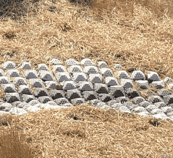 Concrete mat with straw to encourage vegetation.