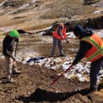 A team of workers applying biotic amendments to the mountain sites with hand tools.