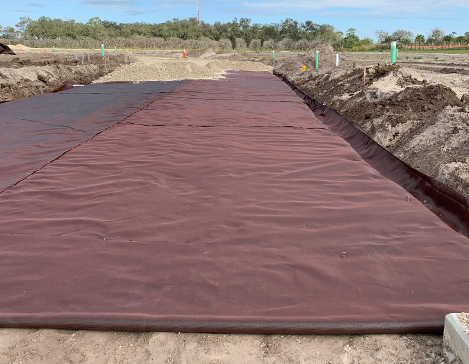 Large factory-sewn Mirafi RS580i geotextiles being installed down miles of roadways in Florida to stabilize soils.