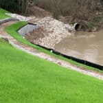 A thick grassy hillside next to a high-flow river