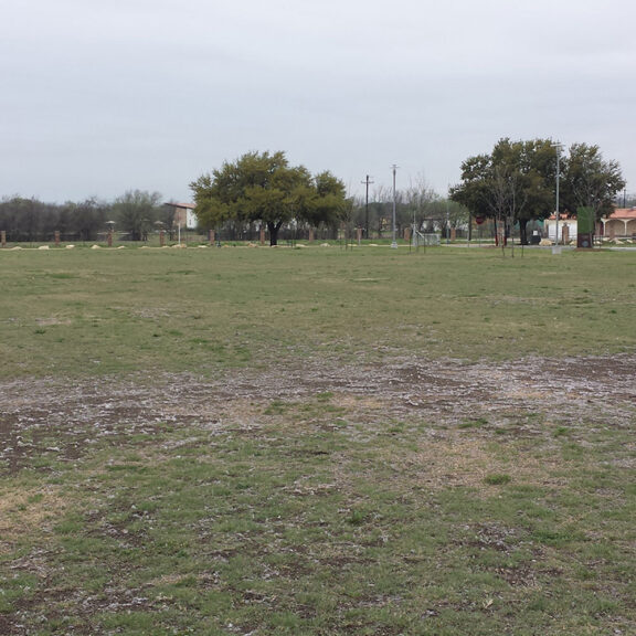 Large sports field with ruts and mud patches