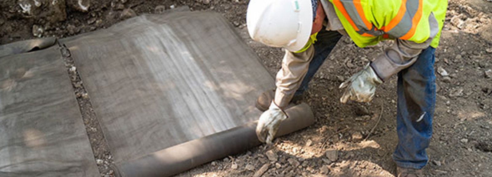 Installing pre-cut strips of concrete canvas as a ditch liner in San Antonia, Texas.