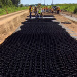 Hand laying a geocell system in order to stabilize a failing road.