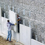 Installation of prefabricated concrete panels for retaining wall.